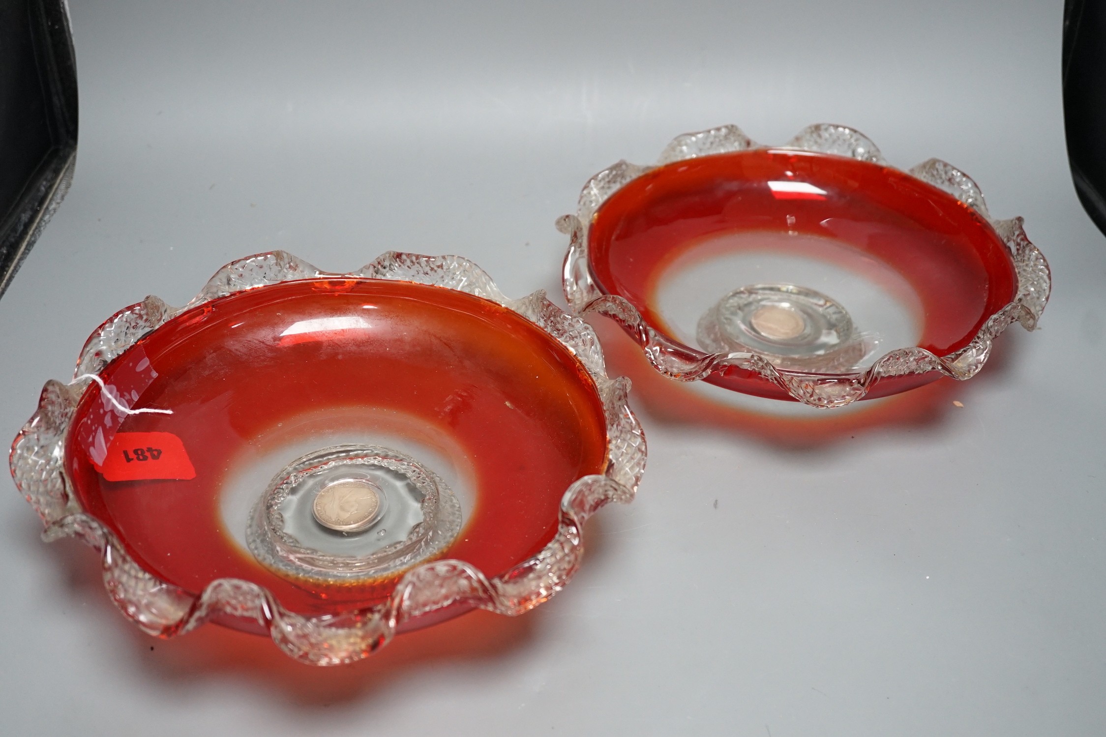 A pair of early 20th century ‘fancy’ glass dishes with inset coins to base, 29cm diameter